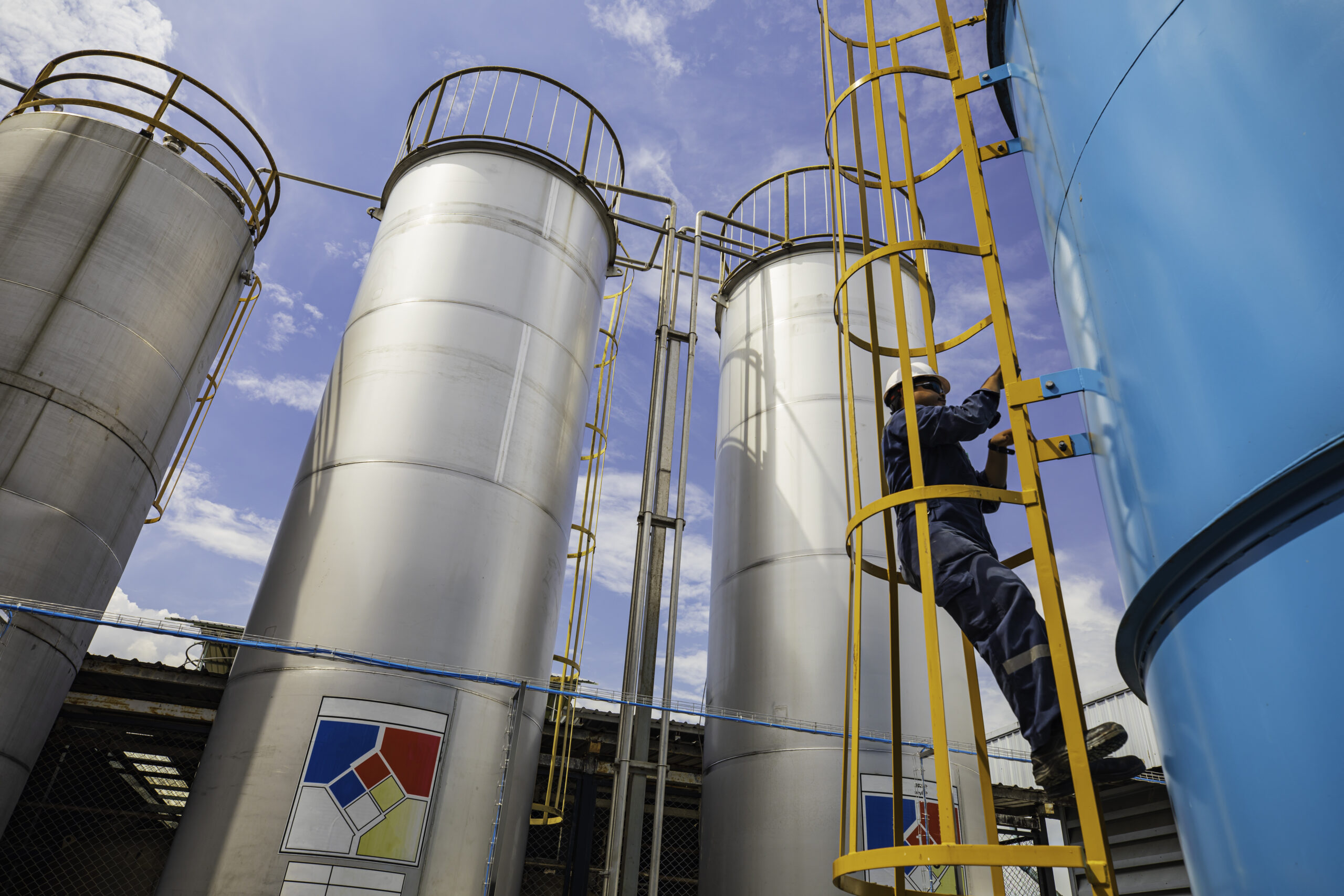 Male worker climbs up the ladder inspection stainless tank work at height safety harness.